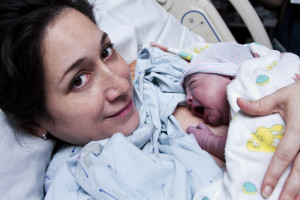 Beautiful new mother happy holding her infant baby after giving birth in hospital.